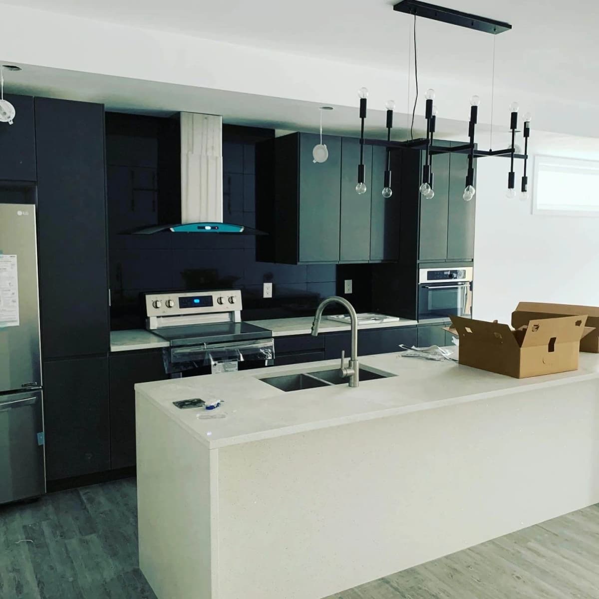 Modern kitchen with custom dark cabinetry and white island by PSD Renovations